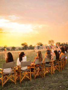 een groep mensen die in stoelen op een veld zitten bij Humble Resort in Masai Mara