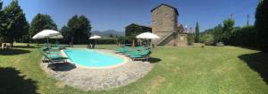 a pool with chairs and umbrellas in a yard at La Casatorre Di Ponticello in Filattiera