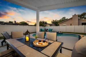 a patio with a table and chairs next to a pool at Luxe Getaway w Pool, Games & Fun Vibes in Palm Harbor