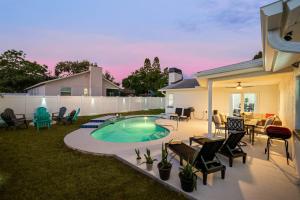 a backyard with a swimming pool and patio furniture at Luxe Getaway w Pool, Games & Fun Vibes in Palm Harbor