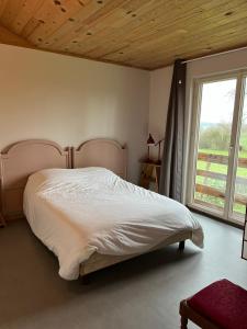Un dormitorio con una cama grande y una ventana. en Le Saint-Germain - Maison en bois en pleine nature, en Saint-Germain-Chassenay