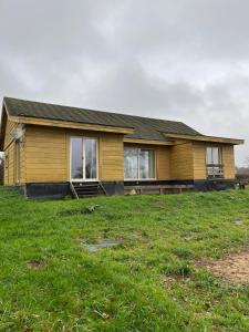 una casa amarilla en un campo de hierba en Le Saint-Germain - Maison en bois en pleine nature, en Saint-Germain-Chassenay