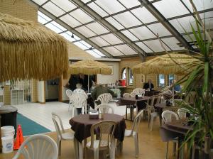 Seaside Camping Resort Studio Cabin 3 في سيسايد: مطعم به طاولات وكراسي ومظلات القش