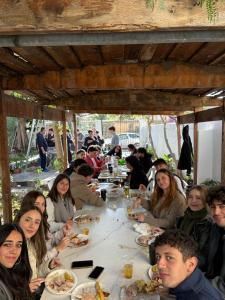 Un grupo de personas sentadas en una mesa comiendo comida en Windmill Hostel, en San Julián