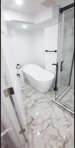 a white bathroom with a tub and a glass shower at Cute and Cozy Studio with Private Parking in Montreal