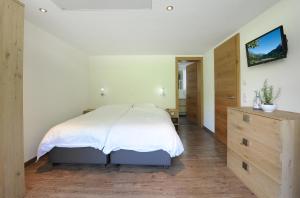 シュレッケンにあるAppartement Rothornblickのベッドルーム(白いベッド1台、木製ドレッサー付)