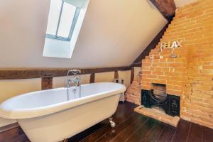 2 Bed in Shelsley Walsh oc-t30222 في Shelsley Walsh: حوض استحمام في حمام به مدفأة من الطوب +18 صورة