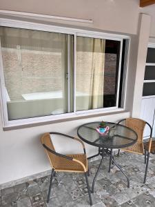 a glass table and chairs on a patio with a window at Vino al Valle in Tupungato