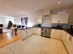 a kitchen with white cabinets and a table in a room at Modern home close to amenities and transport links in Wymondham
