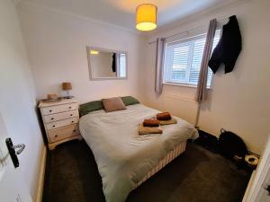 a bedroom with a bed with a dresser and a window at Modern home close to amenities and transport links in Wymondham
