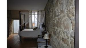 a bedroom with a bed and a stone wall at Le MONSEG in La Celle-sous-Gouzon