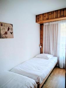 Dos camas individuales en una habitación con ventana. en Centre Thermal 2 chambres studio EV210, en Arni Alp