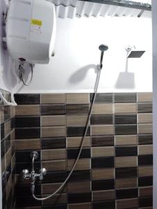 una ducha con una manguera fijada a una pared de azulejos en B5 Homestay, en Shillong