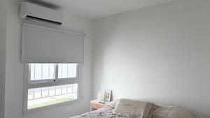 a white bedroom with a window with a blind at Temporario Sur, hasta 4 personas con 3 camas, General Roca in General Roca