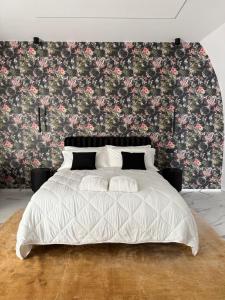 Ein Schlafzimmer mit einem weißen Bett und einer floralen Tapete. in der Unterkunft Kari Suite in Sammichele di Bari