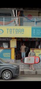 a person holding a surfboard in front of a store at Totora Surf Hostel in Huanchaco