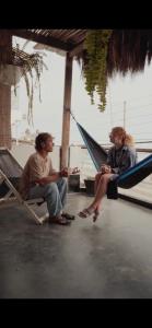 two people sitting on a hammock on a boat at Totora Surf Hostel in Huanchaco