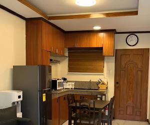 uma cozinha com armários de madeira e um frigorífico preto em Ranch-o-tel Guesthouse em Sampong