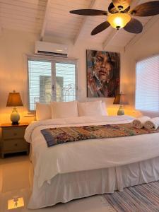 Caye Caulker Boutique Guesthouse 1 في كاي كولكر: غرفة نوم بها سرير كبير ولوحة فنية على الحائط