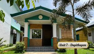 uma pequena casa com um sinal em frente em Ranch-o-tel Guesthouse em Sampong