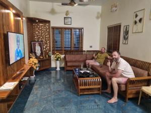 two men sitting on couches in a living room at Woodland Vista Thekkady in Thekkady