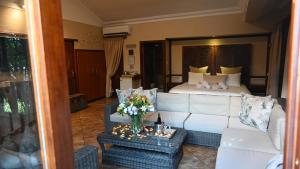 LUXURY EN-SUITE ROOM WITH LOUNGE @ 4 STAR GUEST HOUSE في ميدلبرغ: غرفة معيشة مع أريكة بيضاء وسرير