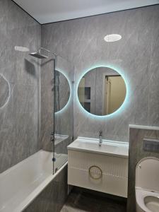 een badkamer met een bad, een wastafel en een spiegel bij Amal in Zhezdi