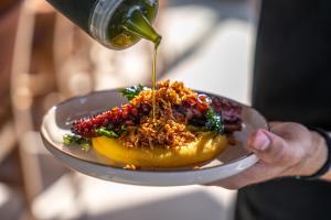 Happy Cretan Suites في أغيا بيلاغيا: شخص يحمل صحن عليه طعام