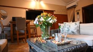 LUXURY EN-SUITE ROOM WITH LOUNGE @ 4 STAR GUEST HOUSE في ميدلبرغ: غرفة معيشة مع مزهرية من الزهور على طاولة