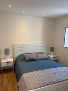 une chambre avec un grand lit avec deux tables de nuit dans l'établissement Casa das Orquídeas Meco, à Sesimbra