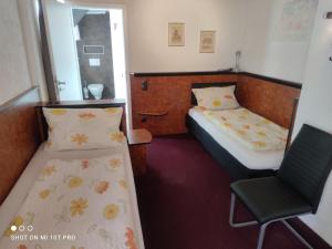 a small room with two beds and a chair at Hotel Corveyer Hof in Höxter
