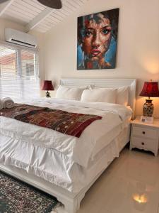 Caye Caulker Boutique Guesthouse 1 في كاي كولكر: غرفة نوم بها سرير ولوحة على الحائط +6 صور