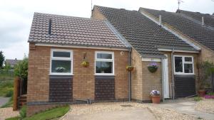 a brown brick house with white windows and flowers at The Little Annexe in Stamford