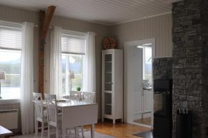 een eetkamer met een tafel, stoelen en ramen bij Cabin in Mestervik in Meistervik +19 foto's