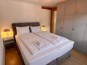 a bedroom with a large white bed with two towels at Breathtaking Lake & Mountain View Apartment 2 in Niederried