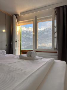 a white bed with a view of mountains from a window at Breathtaking Lake & Mountain View Apartment 2 in Niederried