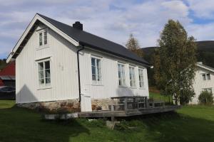 een wit huis met een veranda in een veld bij Cabin in Mestervik in Meistervik