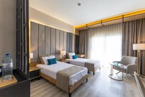 a hotel room with two beds and a chair at Paradisos Hotel in Trakhoni