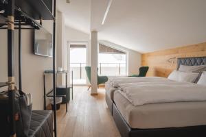 a bedroom with two beds and a chair in it at Black Summit Samnaun Boutique Hotel in Samnaun