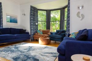 a living room with blue couches and a large window at St Marks Stays in Sedbergh