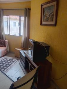 un soggiorno con TV e scrivania con sedia di Apartamento Recanto dos pássaros a Peruíbe