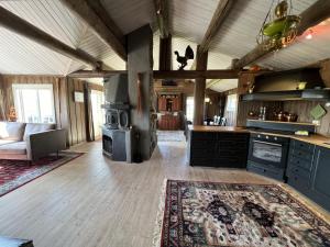 a large kitchen with a stove and a living room at Welcoming Cabin With Fireplace & Modern Kitchen in Beitostøl