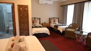 LUXURY FAMILY EN-SUITE ROOM @ 4 STAR GUEST HOUSE في ميدلبرغ: غرفة فندقية بسريرين وحمام