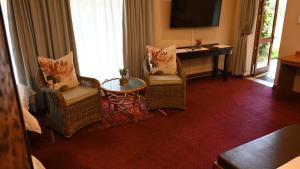 LUXURY FAMILY EN-SUITE ROOM @ 4 STAR GUEST HOUSE في ميدلبرغ: غرفة معيشة مع كرسيين وطاولة +17 صورة