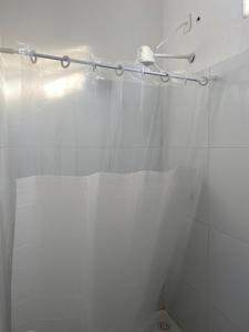 a shower with a white shower curtain in a bathroom at Casa Moreré in Ilha de Boipeba