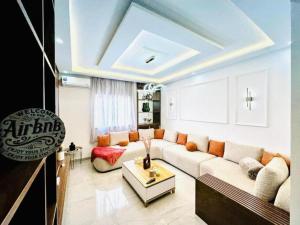 una sala de estar con un sofá y una mesa en Elegant 3BR Stay 5min to Hay Riad, en Temara
