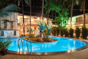 Parkwood Exotica Resort - Alibaug في Chorondpāda: مسبح امام الفندق في الليل