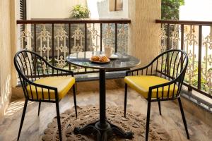 Parkwood Exotica Resort - Alibaug في Chorondpāda: طاولة مع كرسيين وصحن طعام على شرفة