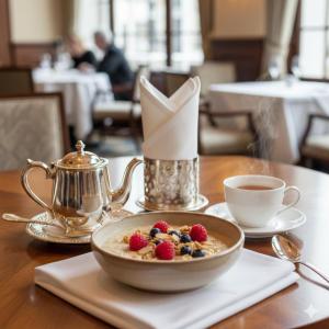 Un tazón de cereales y bayas sobre una mesa con una taza de café. en Hotel Pavo, en Tiflis