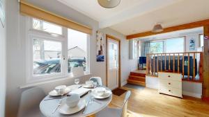 a dining room with a table and chairs and windows at C23 Wilmar, Riviere Towans in Hayle